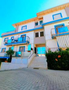 フィウミチーノにあるBeach Vista Apartment, Fiumicinoの青いバルコニーと階段のある白い大きな建物