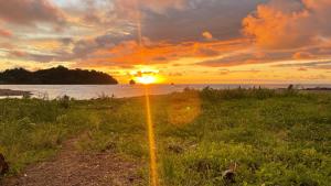 a sunset on the beach with the sun in the distance at Chachamar in Panguí