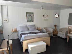 a bedroom with a bed and two chairs at Les Jardins d'Eva et Gotham in Civières