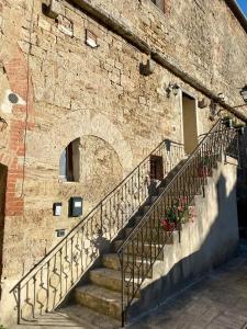 a stone building with stairs next to a brick wall at Dimora San Francesco in Asciano