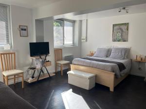 a bedroom with a bed and two chairs and a television at Les Jardins d'Eva et Gotham in Civières