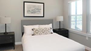 a bedroom with a white bed with two nightstands and two windows at Landing Apartments near North Fort Myers in North Fort Myers