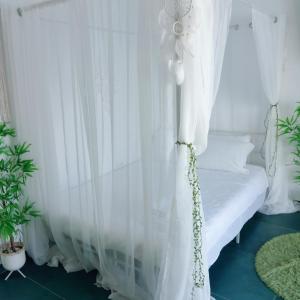 a white canopy bed with white curtains in a room at Sunshine Bungalow in Schitul