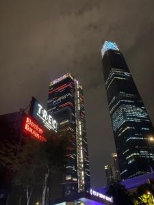 two tall buildings with neon signs in a city at night at Politeknik metro kl in Kuala Lumpur