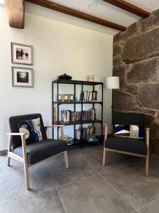 a living room with two chairs and a book shelf at A CASIÑA dos LARANXOS in Cenlle