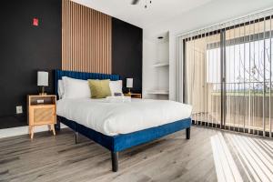 ein Schlafzimmer mit einem blauen Bett und einem großen Fenster in der Unterkunft Boulevard Stays 2BR by Stadium Pool Parking Gym 10 in Glendale