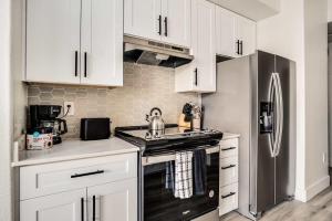 eine Küche mit weißen Schränken und einem Edelstahlkühlschrank in der Unterkunft Boulevard Stays 2BR by Stadium Pool Parking Gym 10 in Glendale