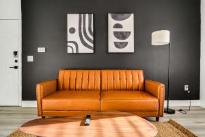 ein orangefarbenes Sofa im Wohnzimmer mit einem Tisch in der Unterkunft Boulevard Stays 1BR by Stadium Pool Parking Gym 01 in Glendale