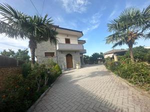 a house with palm trees and a brick driveway at Taku Rooms Vlora 2 in Vlorë
