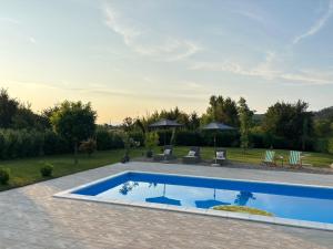 a pool in a yard with chairs and umbrellas at Villa Stone House in Debeljaci