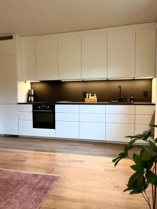 a kitchen with white cabinets and a black wall at Modern apartment with a balcony and free parking in Oslo