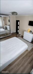 a bedroom with a large white bed and a mirror at Casa Maxim - relaxare în verde in Pantelimon