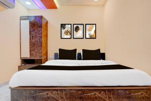 een groot bed in een kamer met drie foto's aan de muur bij OYO TRIPAL SSS HOTEL in Pānchgaon