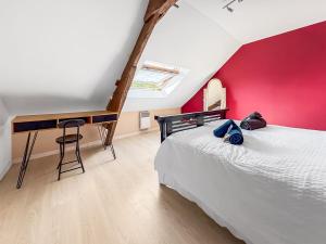 a bedroom with a bed with a red wall and a desk at La Maison du Lac in La Ferté-Macé