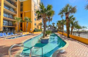 a swimming pool with palm trees next to a building at Caravelle Resort in Myrtle Beach
