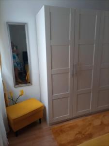 a room with white cabinets and a yellow stool and a mirror at House Jasmina in Mali Lošinj +5 photos