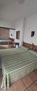 a bedroom with two beds with a striped bedspread at Hotel Rural La Enoteca del Marques in Fermoselle