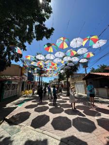 eine Gruppe von Menschen, die mit Sonnenschirmen die Straße hinuntergehen in der Unterkunft Mirante Porto Galinhas beira-mar in Porto De Galinhas