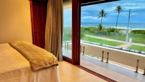 ein Schlafzimmer mit großem Fenster mit Blick auf das Meer in der Unterkunft Mansão Pé na Areia 8 Suítes Alphaville Guarajuba in Barra de Jacuípe + 35 Fotos