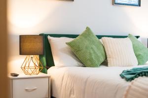a bed with green and white pillows and a lamp at Cozy Ground Floor Getaway Stylish & Central 1BR in Canterbury