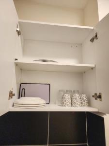 a kitchen with white walls and shelves with dishes at Mayaloft studio near JKIA and SGR in Nairobi