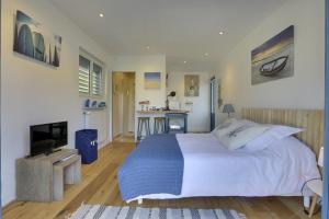 a bedroom with a large white bed and a kitchen at Cap Mango Paradise in Capbreton