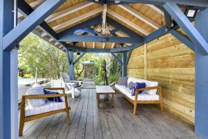 a wooden porch with benches and a chandelier at Cap Mango Paradise in Capbreton