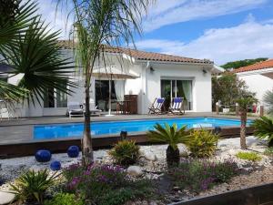 a villa with a swimming pool in front of a house at Cap Mango Paradise in Capbreton