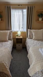 due letti in una stanza con finestra di Happy Feet Pet Friendly Holiday Home Skipsea Sands, Bridlington a Bridlington