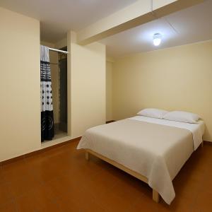 a bedroom with a white bed and a window at Habitación frente a centro comercial in Víctor Larco Herrera