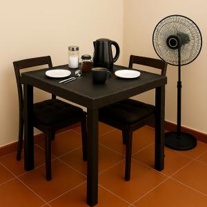 a wooden table with two chairs and a fan at Habitación frente a centro comercial in Víctor Larco Herrera