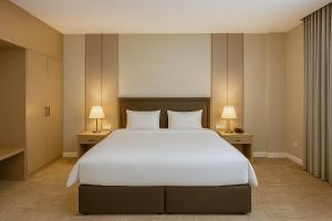 een slaapkamer met een groot wit bed en twee lampen bij Towlan Alrayan in Riyad