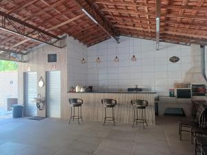 a kitchen with three bar stools in a room at Recanto Julebi in Guaratinguetá