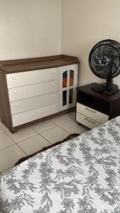 Schlafzimmer mit einem Bett und einer Kommode mit einem Ventilator in der Unterkunft Quarto em apartamento compartilhado em Ananindeua in Ananindeua