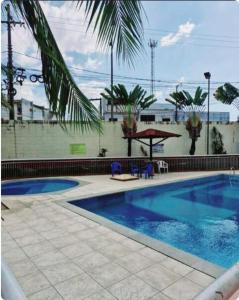 einen Pool mit einer Palme neben einem Gebäude in der Unterkunft Quarto em apartamento compartilhado em Ananindeua in Ananindeua