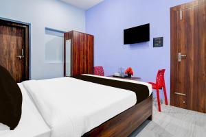 ラーンチーにあるHotel O Ritushreeのベッドと机とテレビのある寝室
