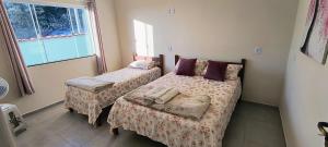 a bedroom with two beds and a window at Casa Beija Flor in São Thomé das Letras