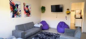 a living room with a couch and purple chairs at Casa Beija Flor in São Thomé das Letras