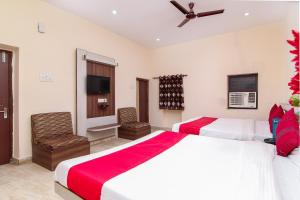 a bedroom with two beds and a flat screen tv at Hotel O Lukergunj Holidays in Muthiganj +29 photos