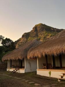 a building with a straw roof with a mountain in the background at NIRA Surf Villas in Maluk