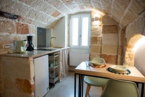 a kitchen with a counter and a table with chairs at Dimora Negli Archi in Monopoli