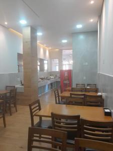 a restaurant with wooden tables and chairs and a kitchen at Hotel Algaroba in Bom Jesus da Lapa