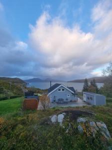 una casa bianca in un campo vicino a uno specchio d'acqua di Discover the ultimate aurora escape with a cozy outdoor sauna and hot tub a Karlsøy