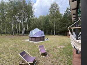 two lawn chairs and a tent in a yard at Cisza lasu in Kadłubówka