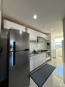 a stainless steel refrigerator in a kitchen with white cabinets at SUNSHINE- Centro ponta grossa in Ponta Grossa +15 photos