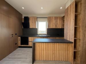 eine Küche mit Holzschränken und einer schwarzen Arbeitsplatte in der Unterkunft Xhoil Hotel in Lushnjë
