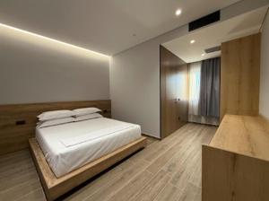 ein Schlafzimmer mit einem weißen Bett und einem Fenster in der Unterkunft Xhoil Hotel in Lushnjë