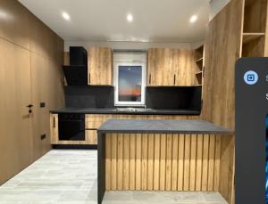 Eine Küche mit Holzschränken und schwarzen Haushaltsgeräten in der Unterkunft Xhoil Hotel in Lushnjë