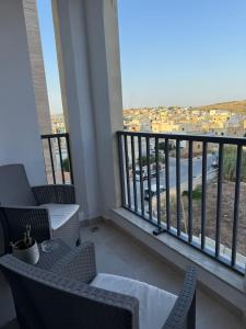 a balcony with chairs and a view of a city at Gemini Court Apartment in Marsaxlokk