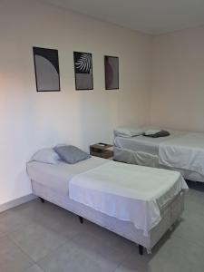 twee bedden in een kamer met drie foto's aan de muur bij Hotel Castro Alves in Marília